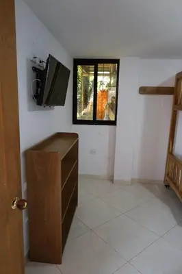 a room with a television and a desk with a window at Apartahotel El Horizonte in Guatapé