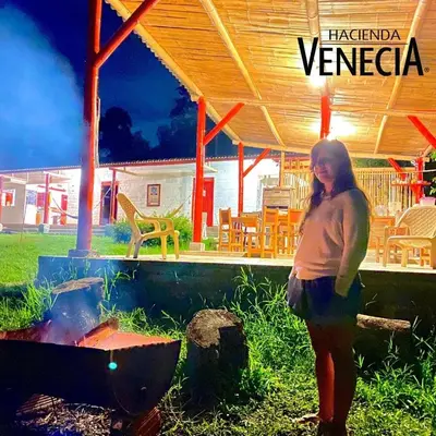 a woman standing in front of a grill at Hacienda Venecia Hostel in Manizales