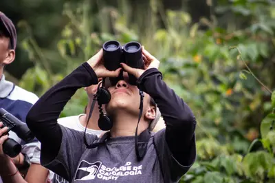a woman holding up her binoculars to her head at Hacienda Venecia Hostel in Manizales
