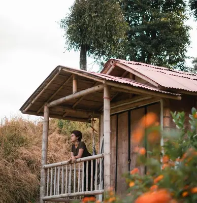 a woman standing on the porch of a small house at Hacienda Venecia Hostel in Manizales