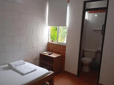 a bathroom with a bed and a toilet and a window at Apartasol San Jeronimo in San Jerónimo