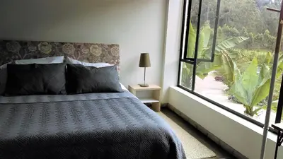 a bedroom with a bed and a large window at Hotel Termales Tierra Viva in Manizales