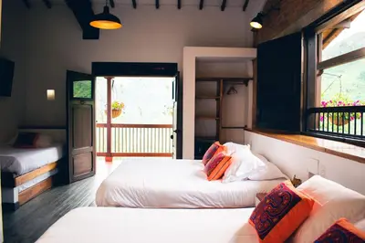 a bedroom with two beds and a window and a door at Finca Boutique el Diamante in Salgar