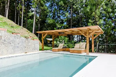 a swimming pool with a wooden pergola and chairs at Finca Boutique el Diamante in Salgar