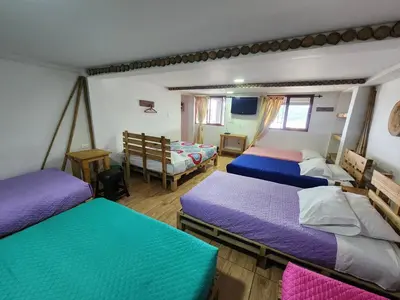 a room with four beds in a room at Hostal Triangulo del Café in Manizales
