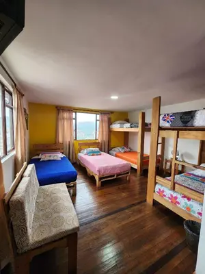 a room with three bunk beds and a couch at Hostal Triangulo del Café in Manizales