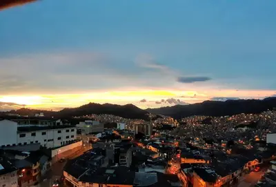 a view of a city at night with the sun setting at Hostal Triangulo del Café in Manizales