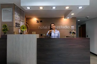 a woman standing behind a counter in a hotel lobby at Hotel Med Estadio in Medellín
