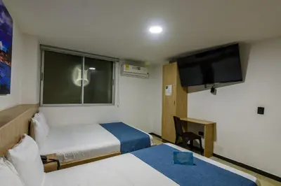 a hotel room with two beds and a flat screen tv at Hotel Med Estadio in Medellín