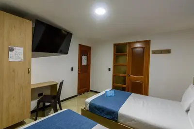 a hotel room with a bed and a desk and a tv at Hotel Med Estadio in Medellín