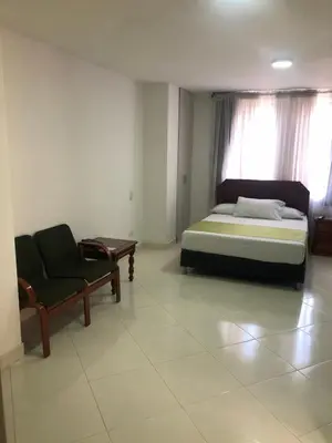 a bedroom with a bed and a chair and a window at Hotel Florida Inn in Medellín