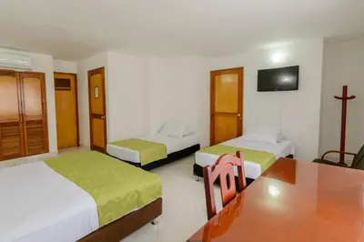 a room with two beds and a table and a tv at Hotel Florida Inn in Medellín