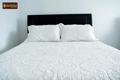 a bed with white sheets and pillows on it at Hotel Madeira in Manizales