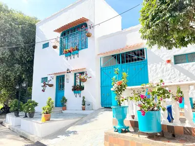 a white house with blue doors and potted plants at Cabaña La Aldea - Santorini Colombiano in Doradal