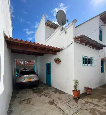 a white house with a car parked outside of it at Cabaña La Aldea - Santorini Colombiano in Doradal