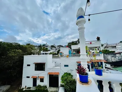 a white building with a pole on a balcony at Cabaña La Aldea - Santorini Colombiano in Doradal
