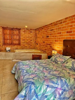 a bedroom with a bed and a brick wall at Finca Turística de Alojamiento Rural Avalon in Jardin