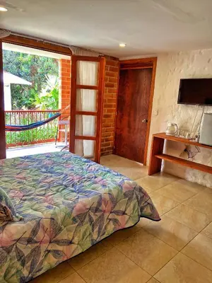 a bedroom with a bed and a balcony with a television at Finca Turística de Alojamiento Rural Avalon in Jardin