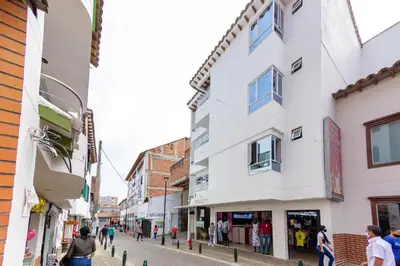 a street with buildings and people walking down the street at Hotel Gutier Rionegro in Rionegro