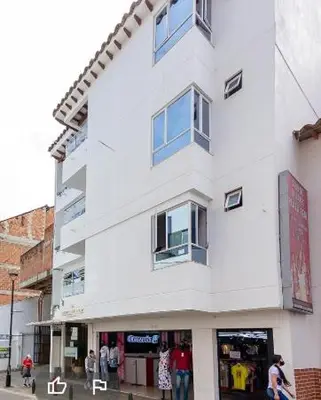 a white building with people standing outside of it at Hotel Gutier Rionegro in Rionegro