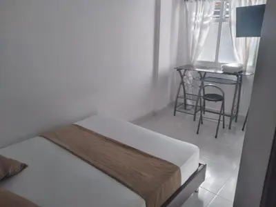 a bedroom with a bed and a table with a chair at Hotel Gutier Rionegro in Rionegro