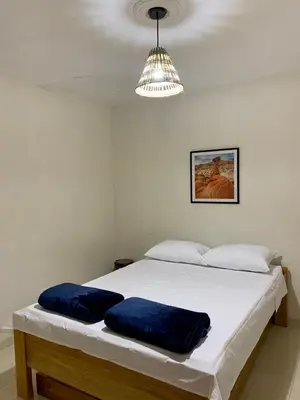 a white bed with two blue pillows on it at Apartamentos Primavera in Jardin