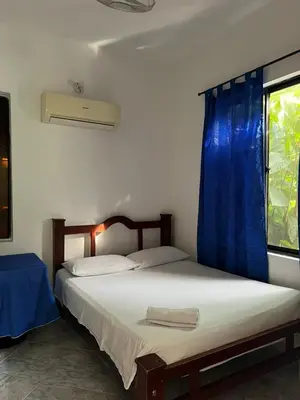 a bedroom with two beds and a window with blue curtains at Hospedaje la Glorieta in Santa Fe de Antioquia