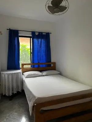 a bedroom with two beds and a window with blue curtains at Hospedaje la Glorieta in Santa Fe de Antioquia