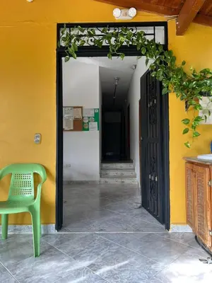 an open door to a yellow wall with a green chair at Hospedaje la Glorieta in Santa Fe de Antioquia