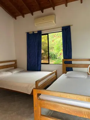 a room with three beds and a window at Hospedaje la Glorieta in Santa Fe de Antioquia