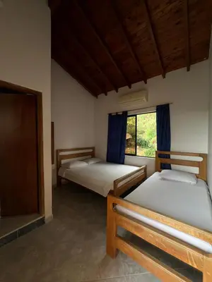 two beds in a room with a window at Hospedaje la Glorieta in Santa Fe de Antioquia