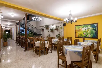 a restaurant with tables and chairs and a staircase at Hotel Valdivia Plaza in Jardin