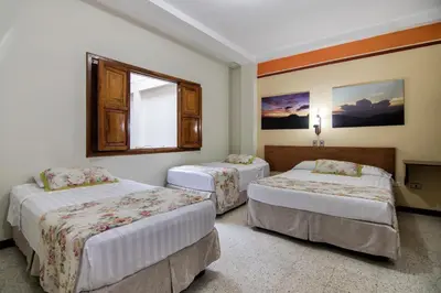 a hotel room with two beds and a window at Hotel Valdivia Plaza in Jardin