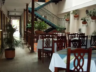 a restaurant with a table and chairs and a staircase at Hotel Valdivia Plaza in Jardin