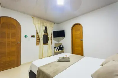 a bedroom with a bed with wooden doors and a tv at Hotel Real Guatapé in Guatapé