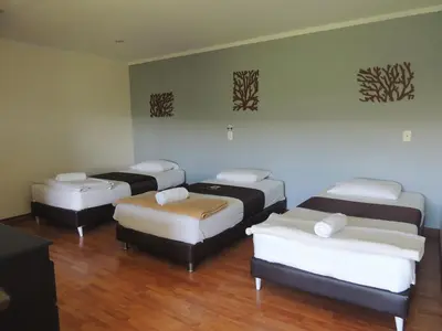 three beds in a room with wood floors at Hotel Villa Colonia in Marinilla