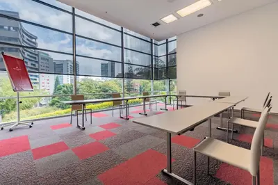 a conference room with tables and chairs and large windows at NH Collection Medellin Royal in Medellín