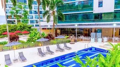a pool with chairs and umbrellas next to a building at NH Collection Medellin Royal in Medellín