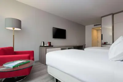a hotel room with a bed and a red chair at NH Collection Medellin Royal in Medellín