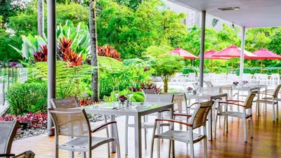 a restaurant with white tables and chairs and red umbrellas at NH Collection Medellin Royal in Medellín