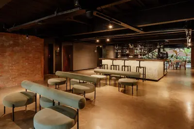 a room with a bar with stools and tables at The Art Hotel Medellin in Medellín