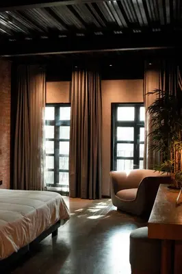 a bedroom with a bed and a couch and windows at The Art Hotel Medellin in Medellín
