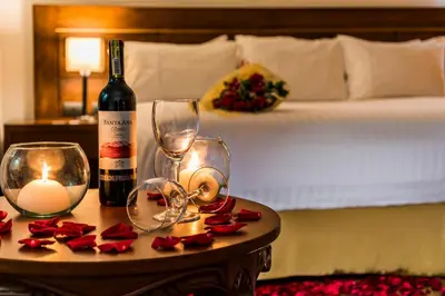 a bottle of wine and candles on a table with a bed at Hotel Portales Del Campestre in Medellín