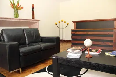 a living room with a black leather couch and a table at Hotel Portales Del Campestre in Medellín