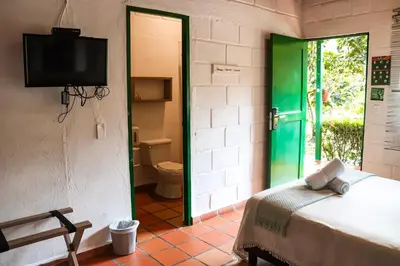 a room with a bed and a television and a bathroom at Los Colores Ecoparque in Doradal