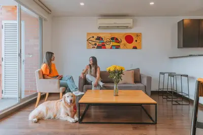 two women sitting in a living room with a dog at Travelers Orange Suites in Medellín