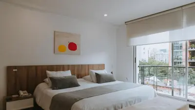 a bedroom with a large bed and a large window at Travelers Orange Suites in Medellín