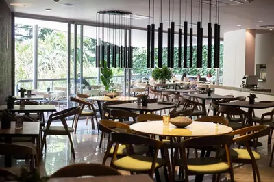 a restaurant with tables and chairs and large windows at Hotel Estelar Blue in Medellín