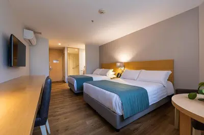 a hotel room with two beds and a table at Hotel Estelar Blue in Medellín