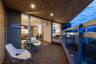 a balcony with a glass table and white chairs at Hotel Estelar Blue in Medellín